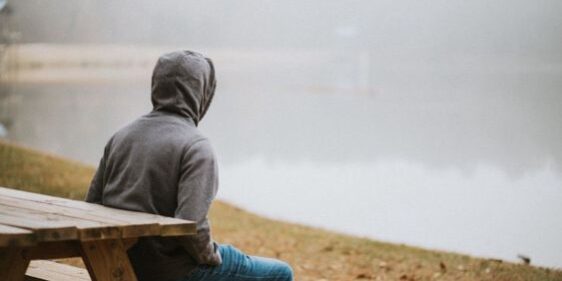 A person sitting on a bench overlooking a lake.
