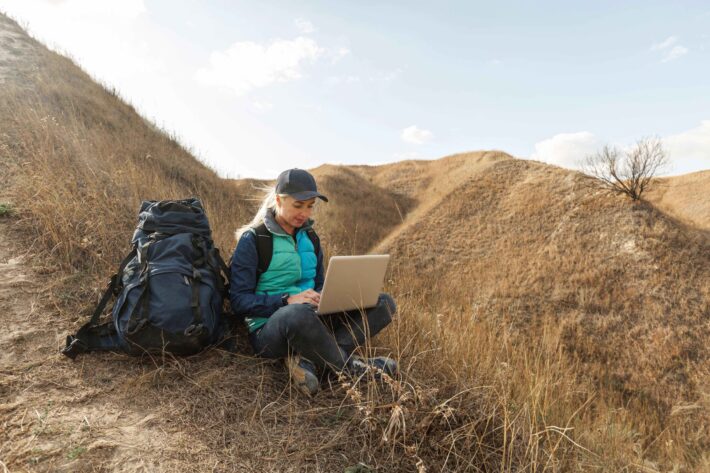 A woman sitting on a hill to with a laptop